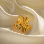 Textured gold flower ring resting on folded satin