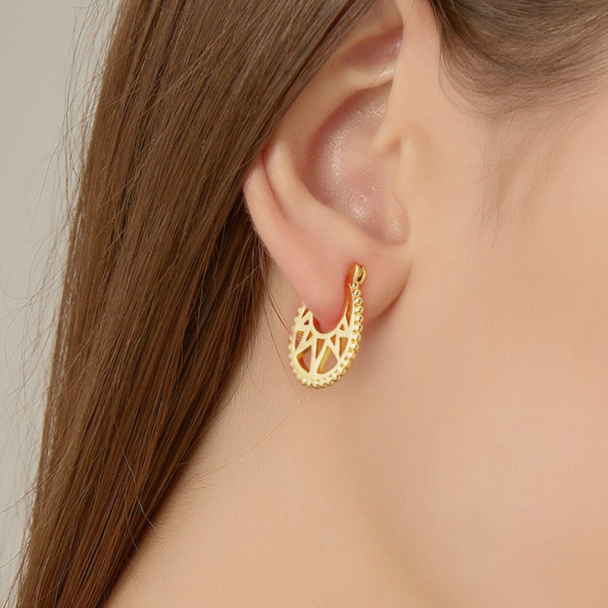 compact geometric openwork hoop earring worn on the earlobe