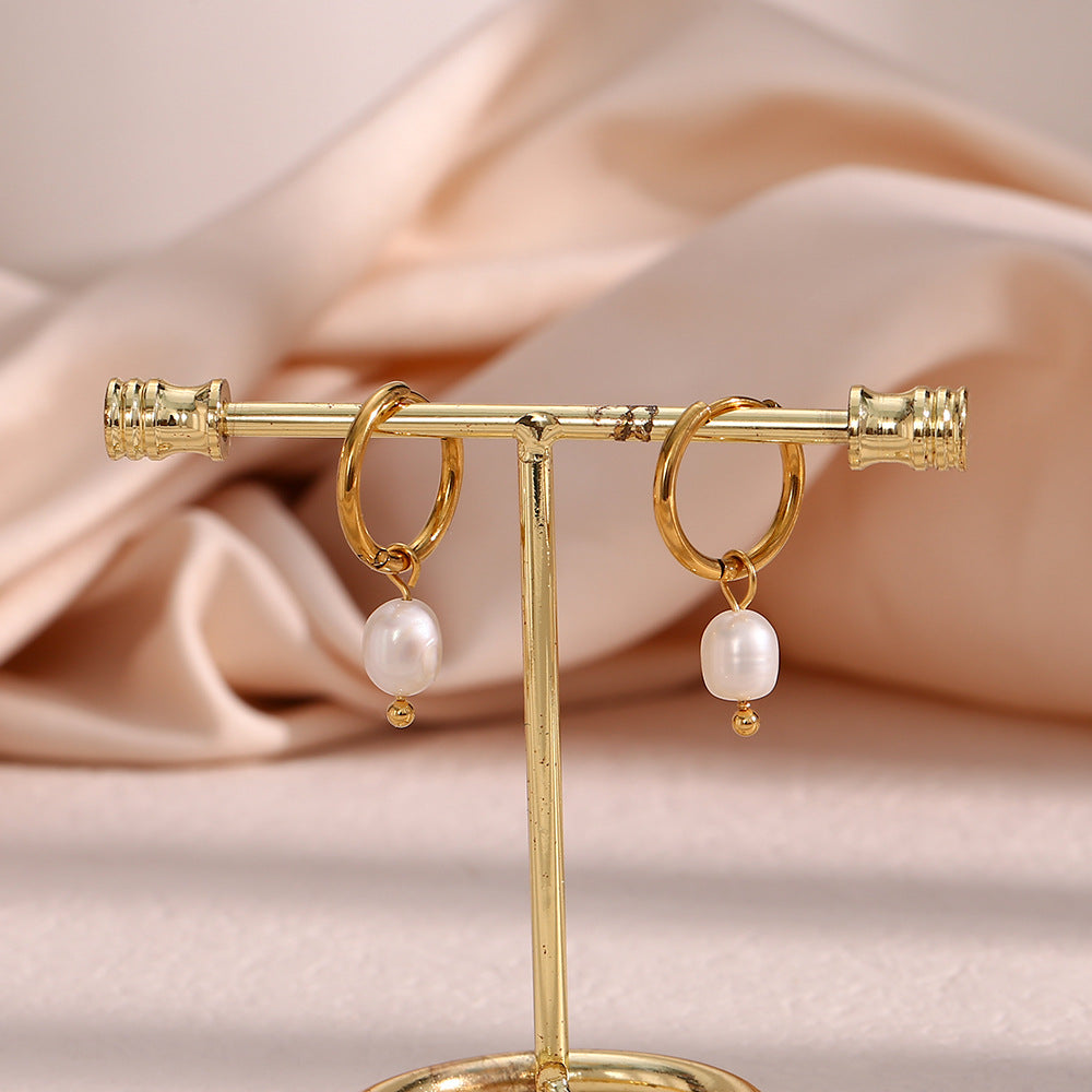 small gold plated pearl drop hoops displayed on an earring stand