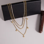 Layered gold tone necklace displayed on a black accessory