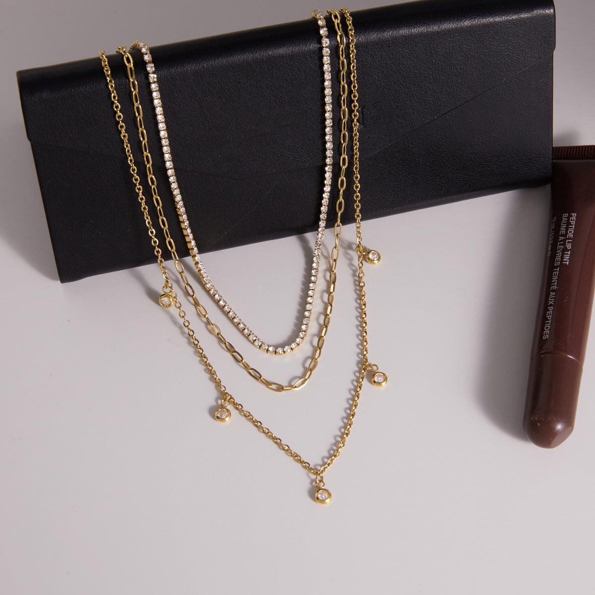 Layered gold tone necklace displayed on a black accessory