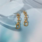 pair of gold plated oval-link drop earrings on blue glass