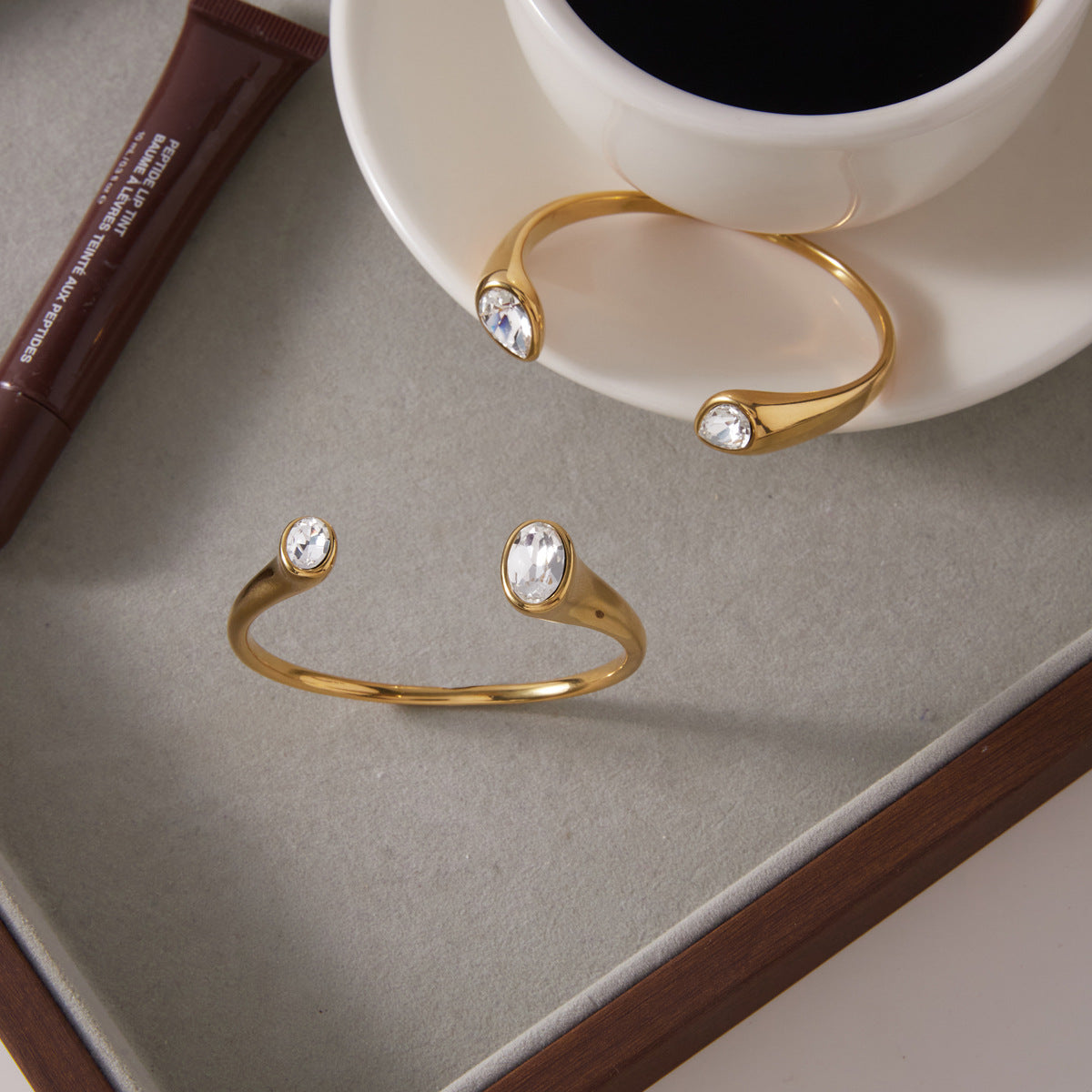Two polished open cuffs displayed beside a cup