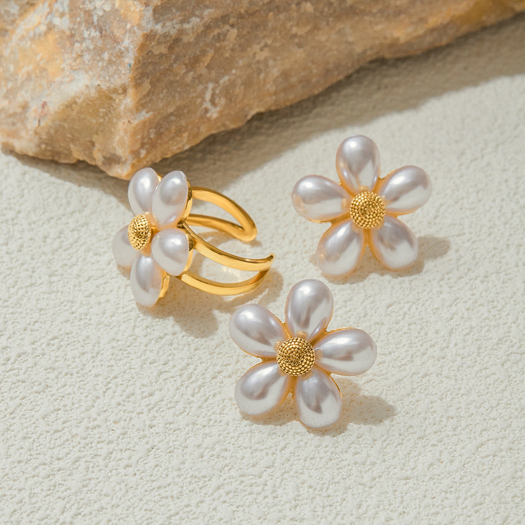 White petal ring and stud earrings displayed on stone