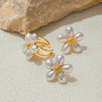 White petal ring and stud earrings displayed on stone