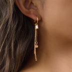 Gold-tone hoop with unequal dangling chains shown in profile
