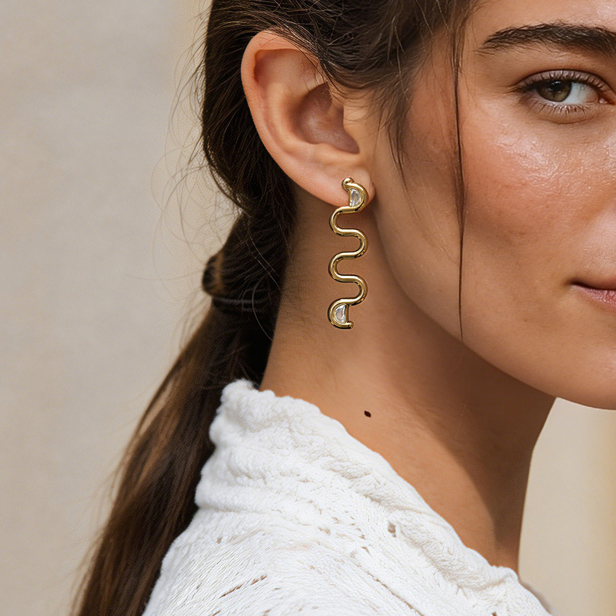 Serpentine earring worn with a white textured top