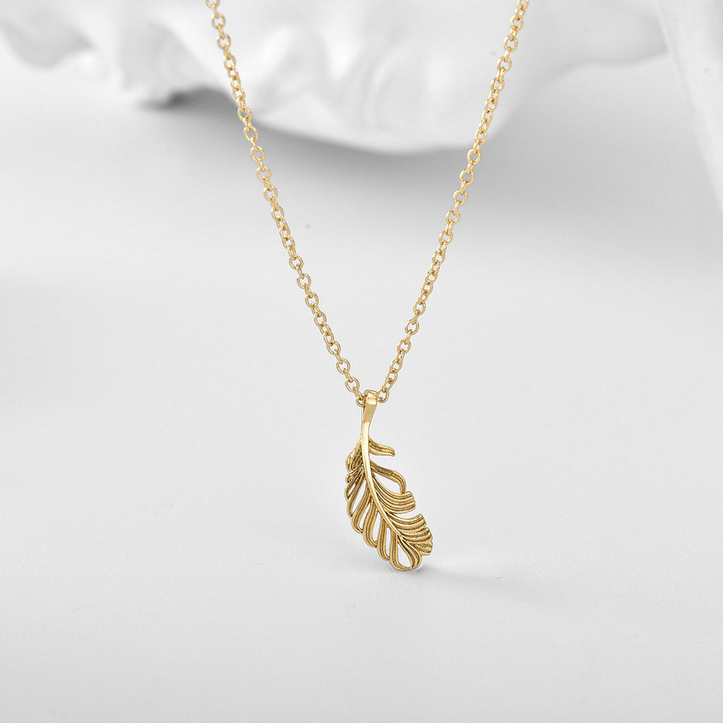 openwork feather pendant necklace styled on a pale surface