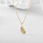 openwork feather pendant necklace styled on a pale surface