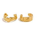 Gold-tone marine and shell cuff designs on white background