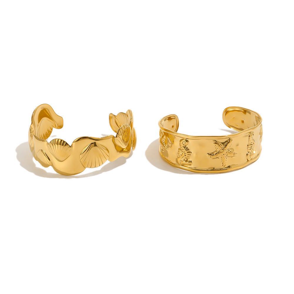 Gold-tone marine and shell cuff designs on white background