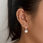 Glass pearl hoop earring worn with other ear jewelry