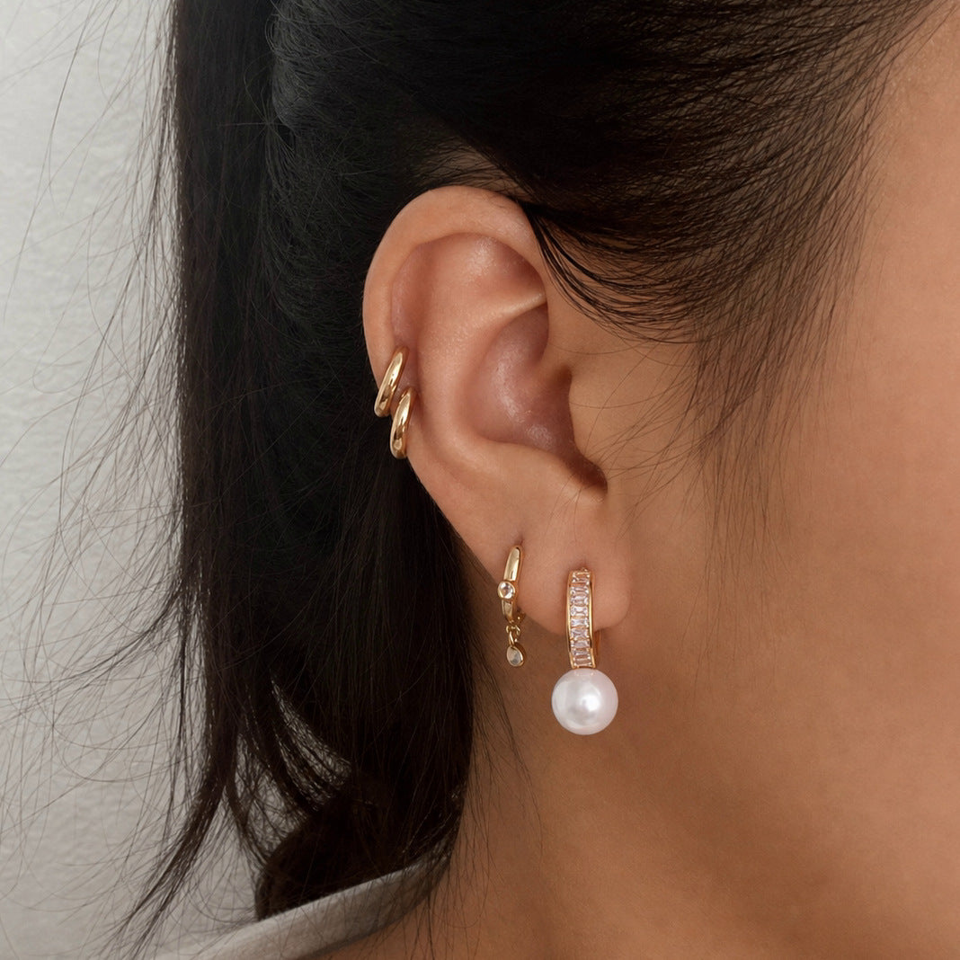 Glass pearl hoop earring worn with other ear jewelry