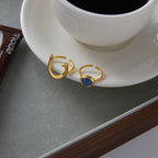 Gold-tone horseshoe stainless steel ring showing the open band and blue center