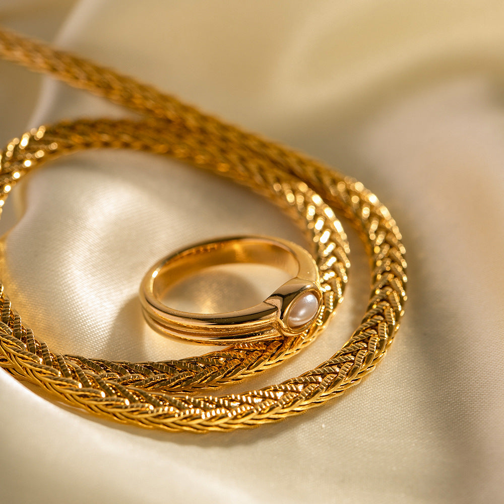 Curved stainless steel ring beside gold chain jewelry