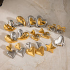 Gold- and silver-finish heart earrings arranged on pale stone