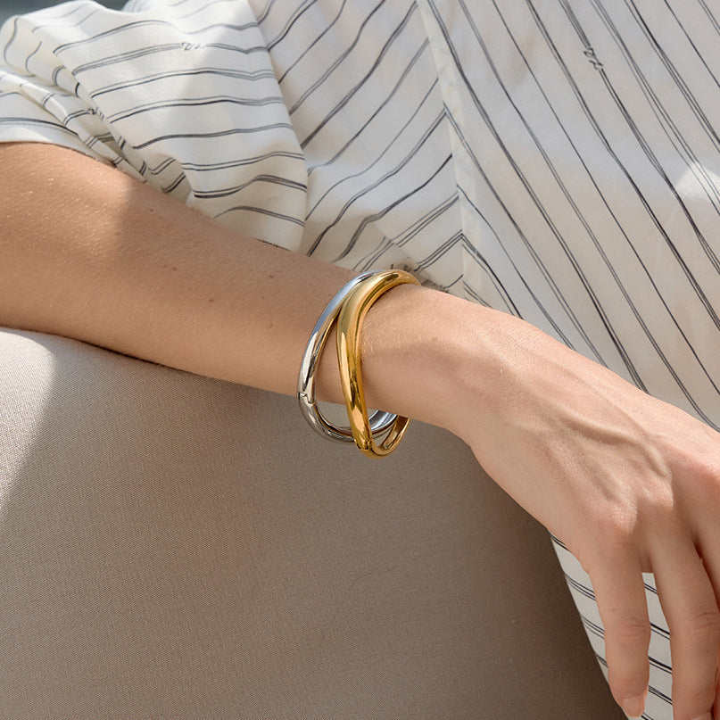 Two metal-color bangles shown on an extended arm