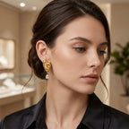 Gold tone sculptural fold earrings with teardrops worn on model