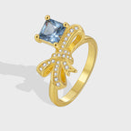 gold plated brass bow cocktail ring with square blue and clear stones