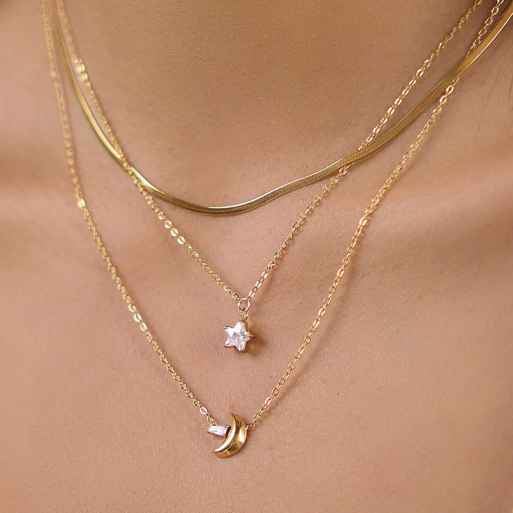 Clear star and gold tone crescent pendants worn together