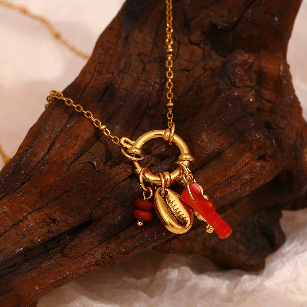 Seahorse and red branch charm cluster against a brown leaf