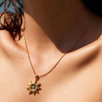 Close-up of sun pendant at neckline