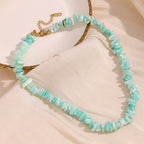 Aqua stone chip necklace with gold tone clasp displayed beside a dish