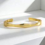 gold plated Möbius-inspired cuff bracelet resting in studio light