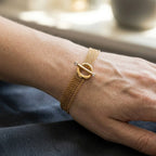 Fine gold-tone chains and round toggle ring viewed from above