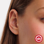 Gold finish three-stone stud shown on ear