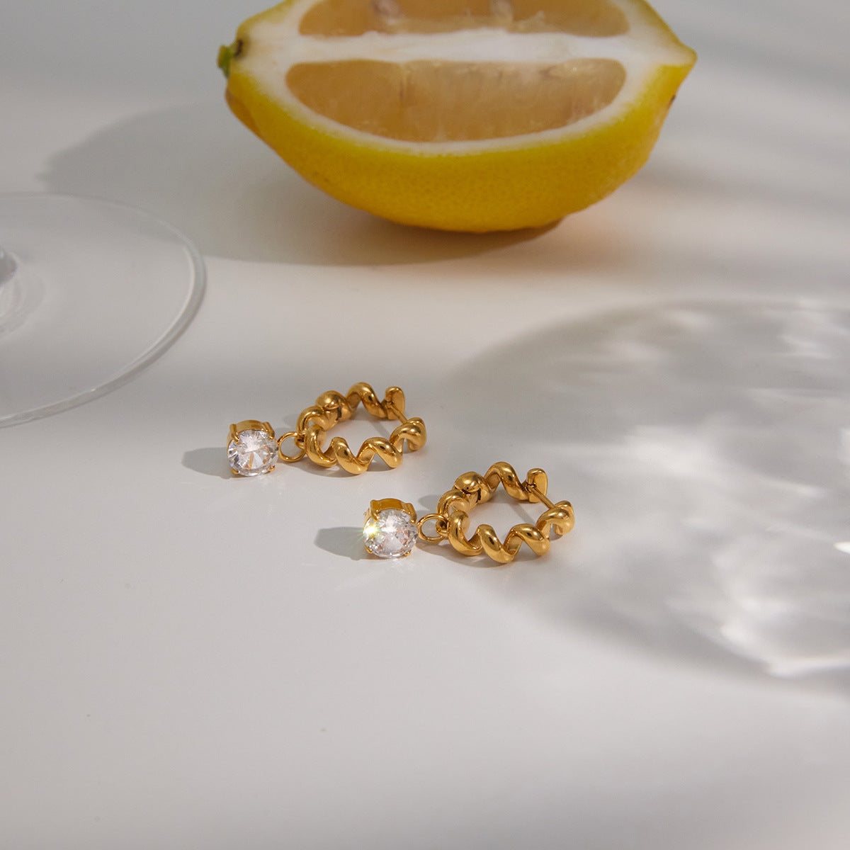Twisted hoops with round clear drops beside a lemon