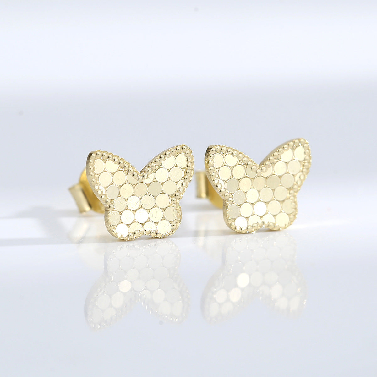 pair of gold plated butterfly studs with circular scale texture
