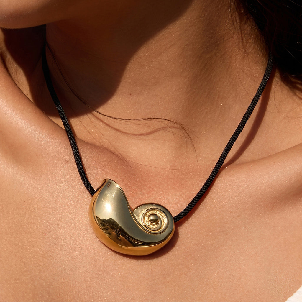 Gold tone shell pendant close-up on black cord