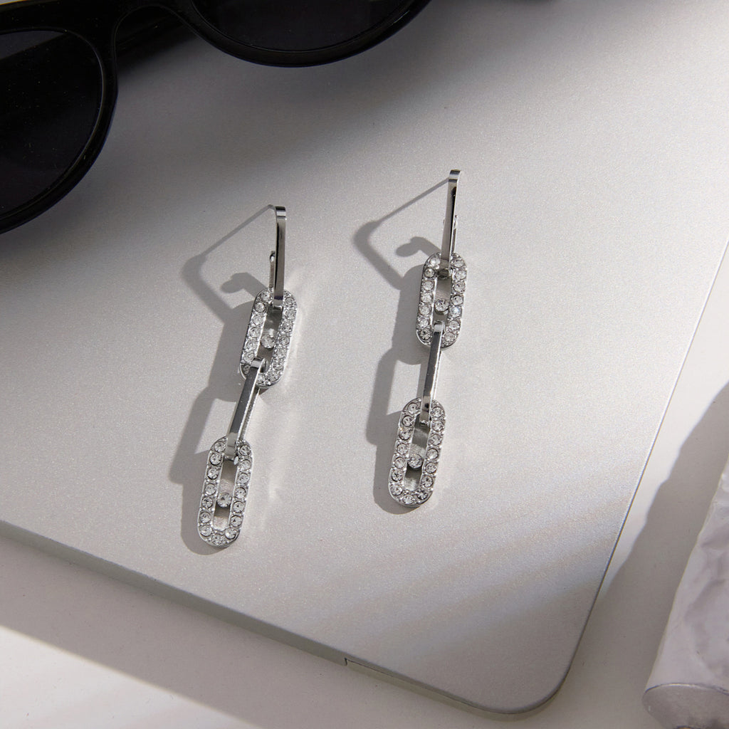 Pair of articulated silver tone earrings on a card