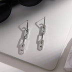 Pair of articulated silver tone earrings on a card