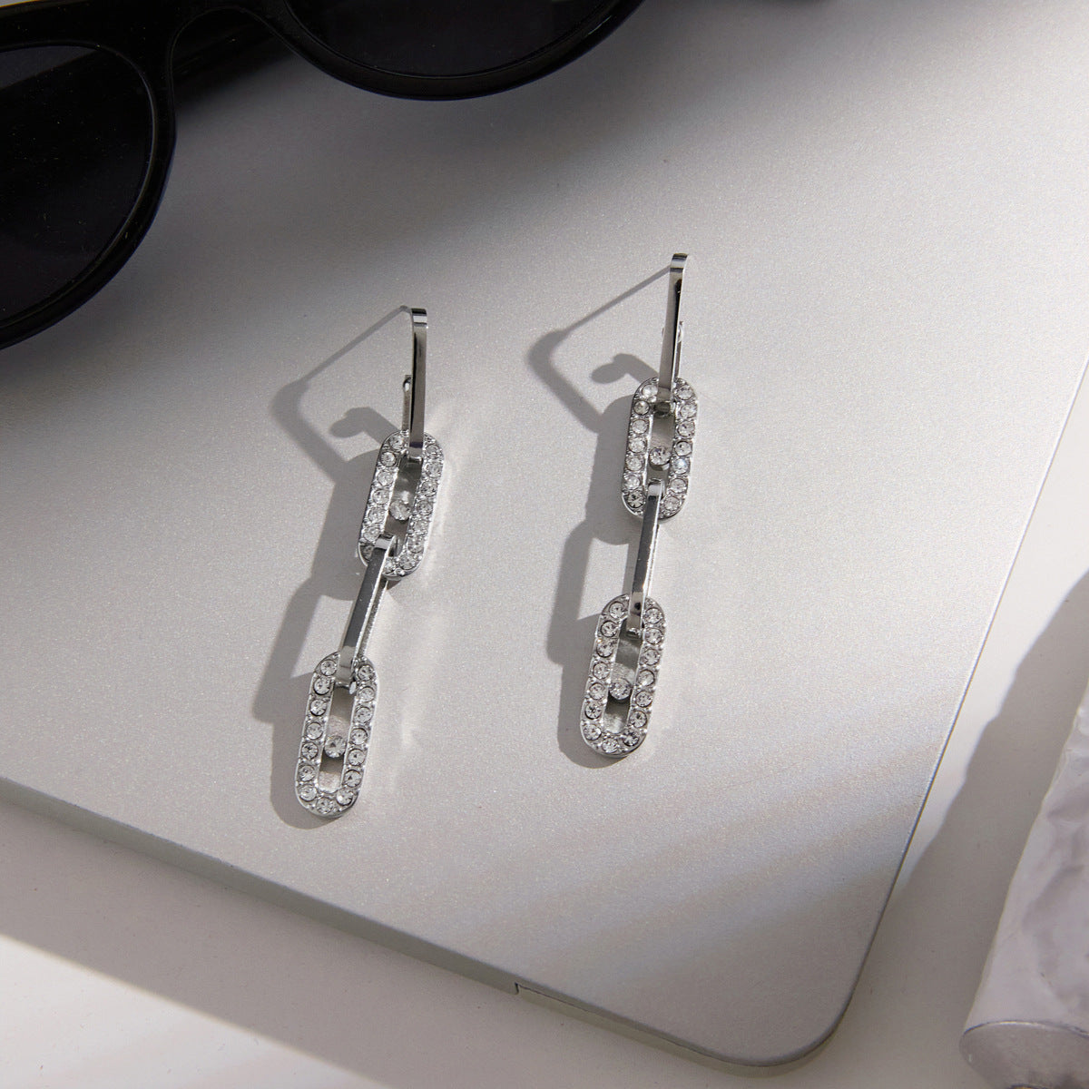 Pair of articulated silver tone earrings on a card