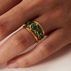 Three oval green stones across a layered ring face