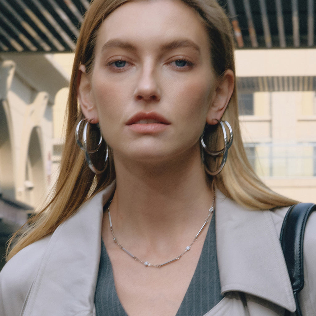 model wearing large silver-finish graduated stainless steel hoop earrings