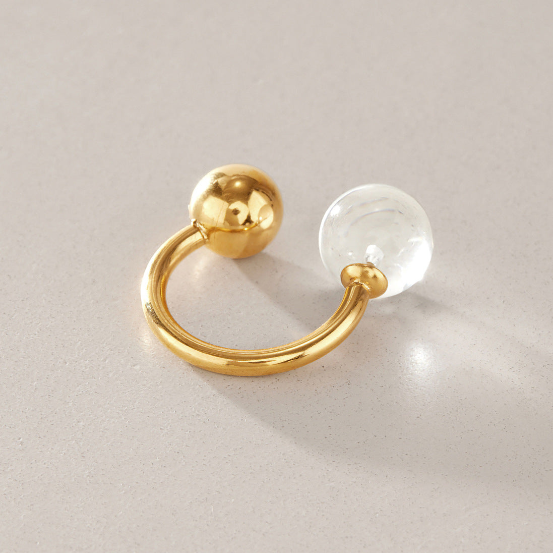 Open ring with transparent sphere and polished metal ball