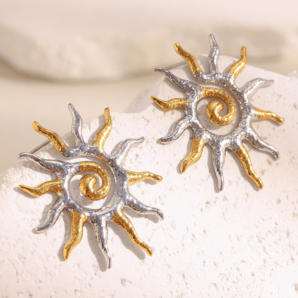 two-tone stainless steel spiral sunburst stud earrings on white stone