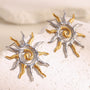 two-tone stainless steel spiral sunburst stud earrings on white stone