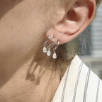 Silver-tone triple-curve earring with pear-shaped drops worn close-up