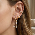 Gold tone arch tassel hoop worn with separate small hoops