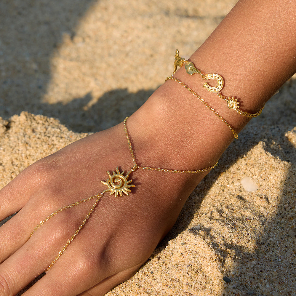 Spiral sun hand chain worn beside a celestial bracelet