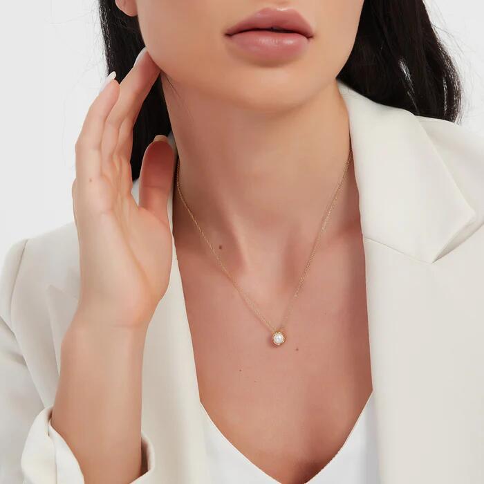 Small pearl-look oval pendant worn on a fine gold-tone chain