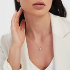 Small pearl-look oval pendant worn on a fine gold-tone chain