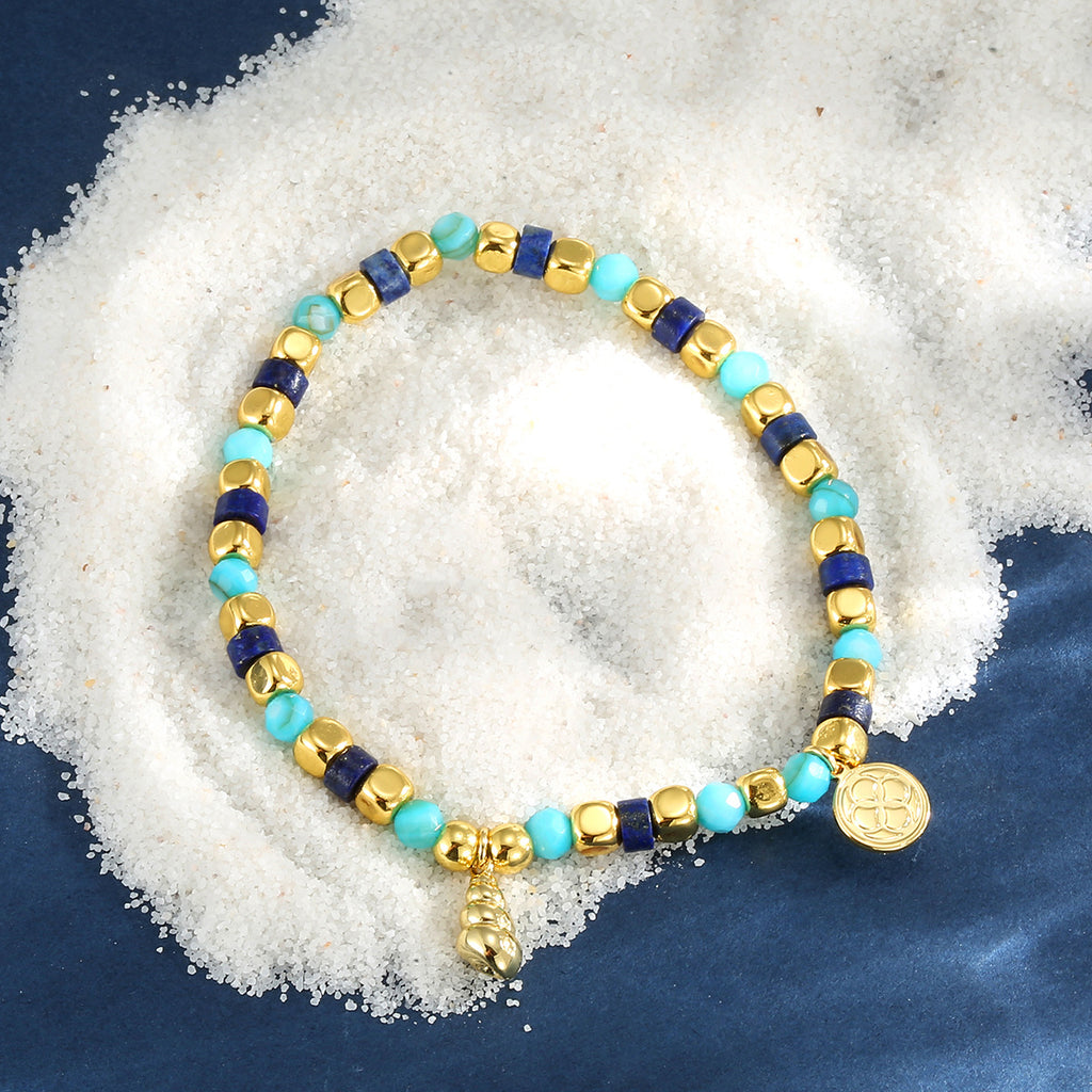 mixed blue bead bracelet styled on navy fabric and white granules
