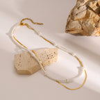 Layered bead and chain necklace arranged beside a stone block
