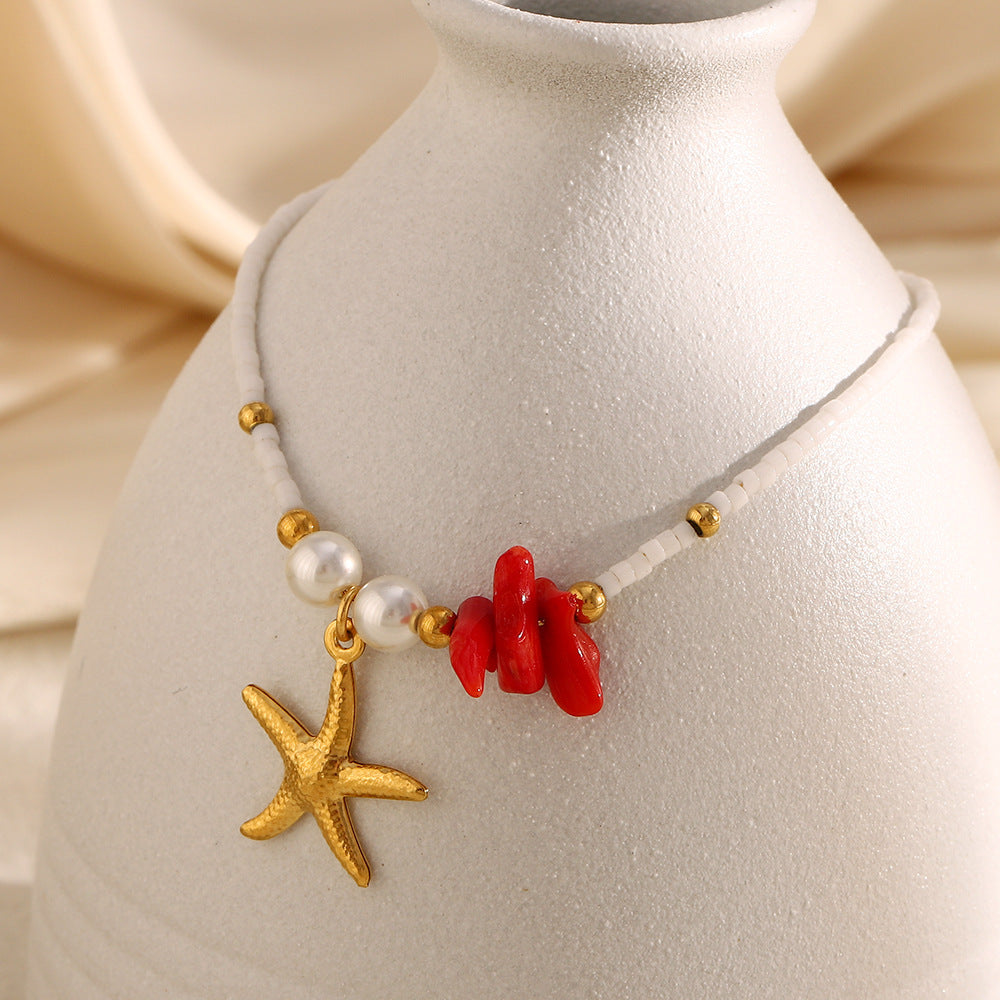 gold plated starfish charm bracelet with red chip and white seed beads on display