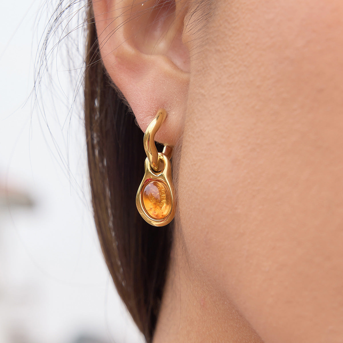 gold plated amber-color resin drop hoop earring worn on ear